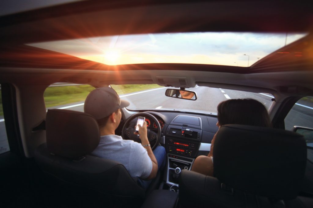 Driver texting while driving on road