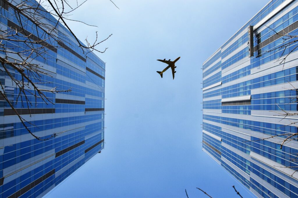 Looking up at airplane between buildings