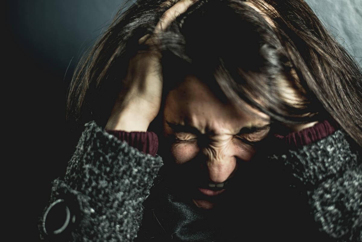 Brunette woman screaming from head pain, anxiety, brain injury