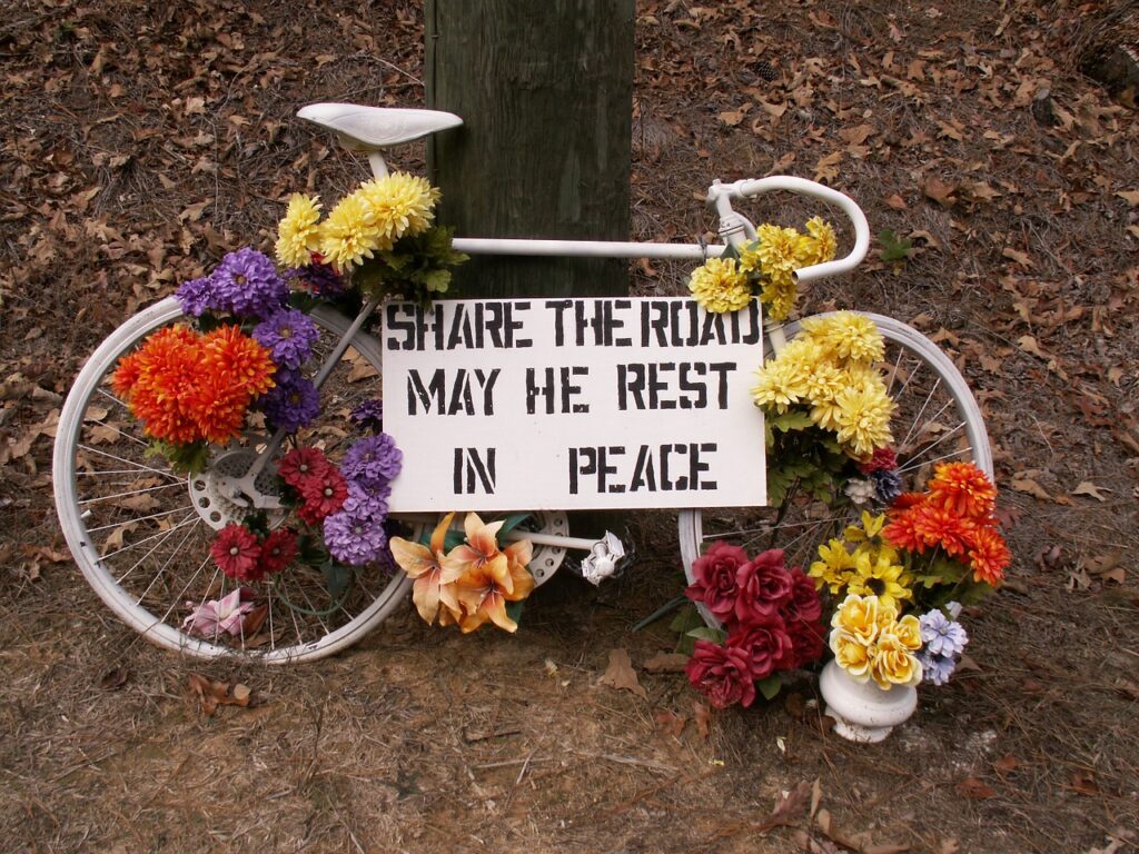 Bike accident memorial with bike and flowers and sign, Share the Road May He Rest in Peace