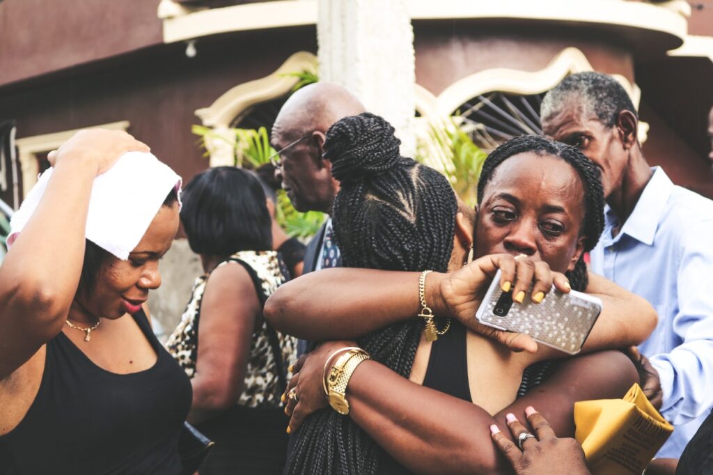 Upset black woman hugging another black woman