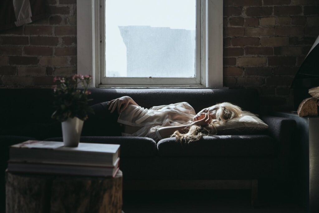 Woman laying on a couch, feeling ill