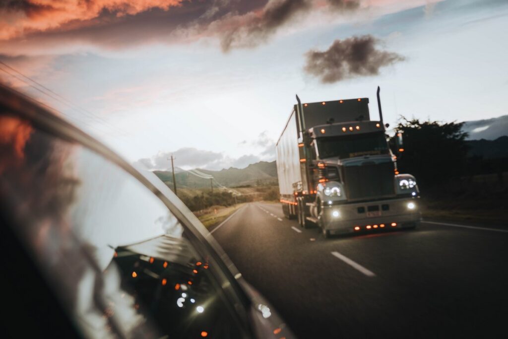 Big rig truck on the highway in a car's rear view mirror