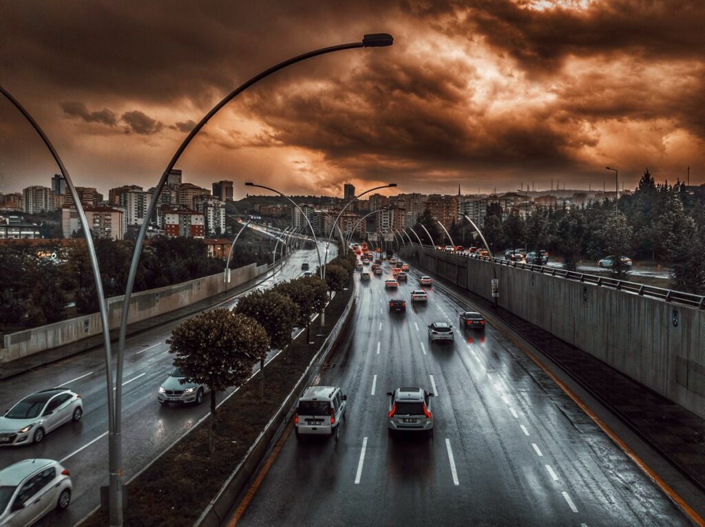 Many cars driving on a freeway, while it is raining